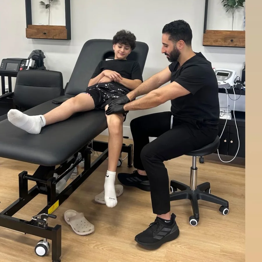 A therapist assessing a young athlete's knee on a treatment table