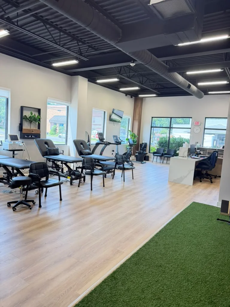 The open treatment floor seen from the turf: tables and chairs by the windows, and the front desk in the corner